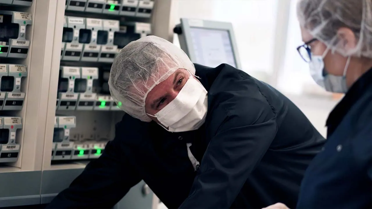 NEXAS Media porträtiert Multidos in Bad Camberg in einem Imagefilm. Ein Mitarbeiter mit Mundschutz und Haarnetz prüft im Reinraum die Wirkstoff-Module.